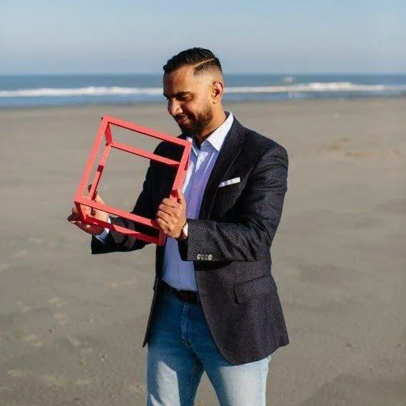 Sfeerbeeld Quion. Een man kijkt naar kubus in zijn handen op het strand.